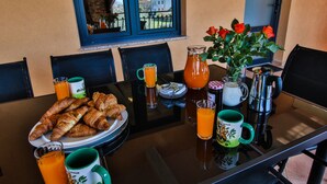 Une table de petit-déjeuner avec des croissants, du jus d’orange et des tasses de café.