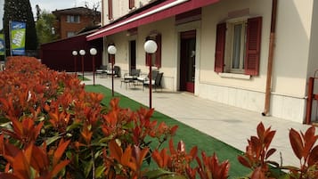 Un hotel con posti a sedere all'aperto e un giardino curato.