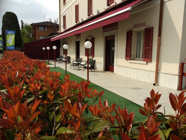 Un hotel con terraza y un jardín bien cuidado.