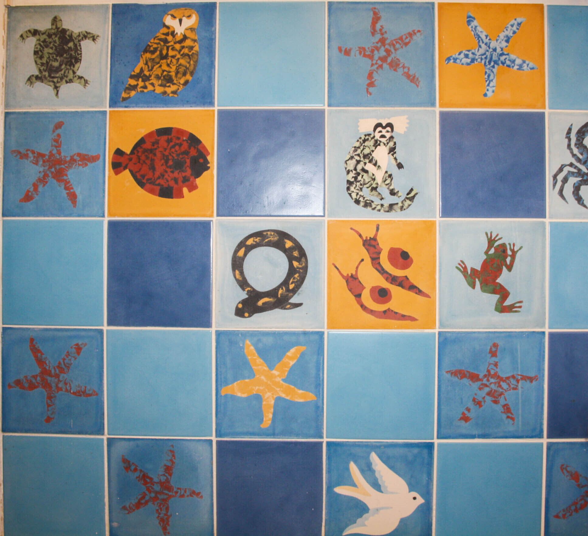 Une mosaïque composée de carreaux ornés de motifs variés représentant des animaux et des objets.