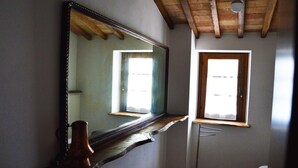 Een badkamer met een grote spiegel, een raam en een plafond met houten balken.
