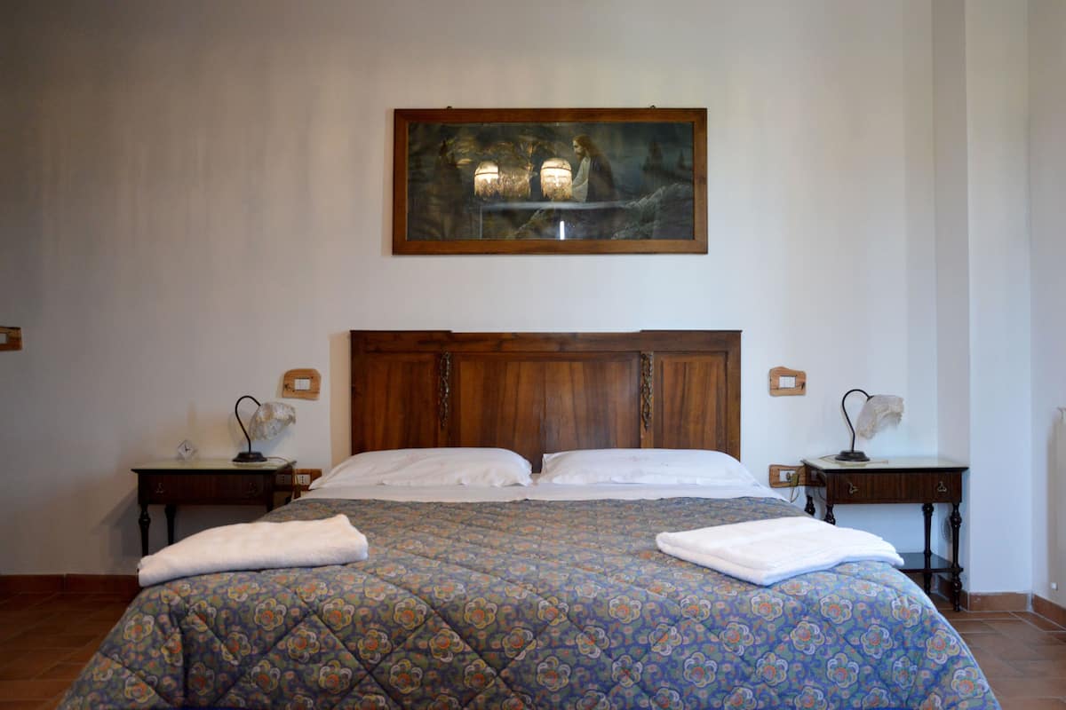 Une chambre à coucher avec un grand lit, deux tables de chevet, une tête de lit en bois et un tableau encadré au-dessus du lit.