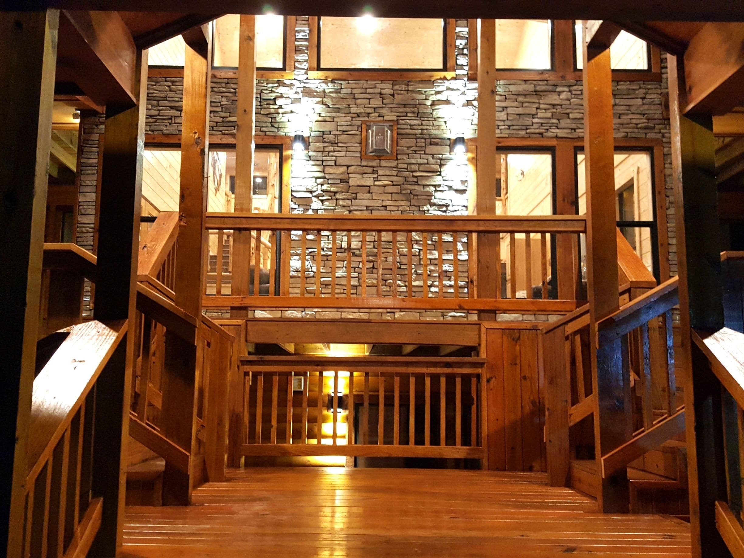 A wooden staircase leading to a balcony with stone walls and wooden railings.