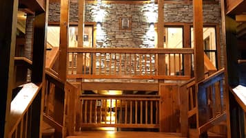 A wooden staircase leading to a balcony with stone walls and wooden railings.