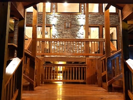 Una escalera de madera que conduce a un balcón con muros de piedra y barandillas de madera.