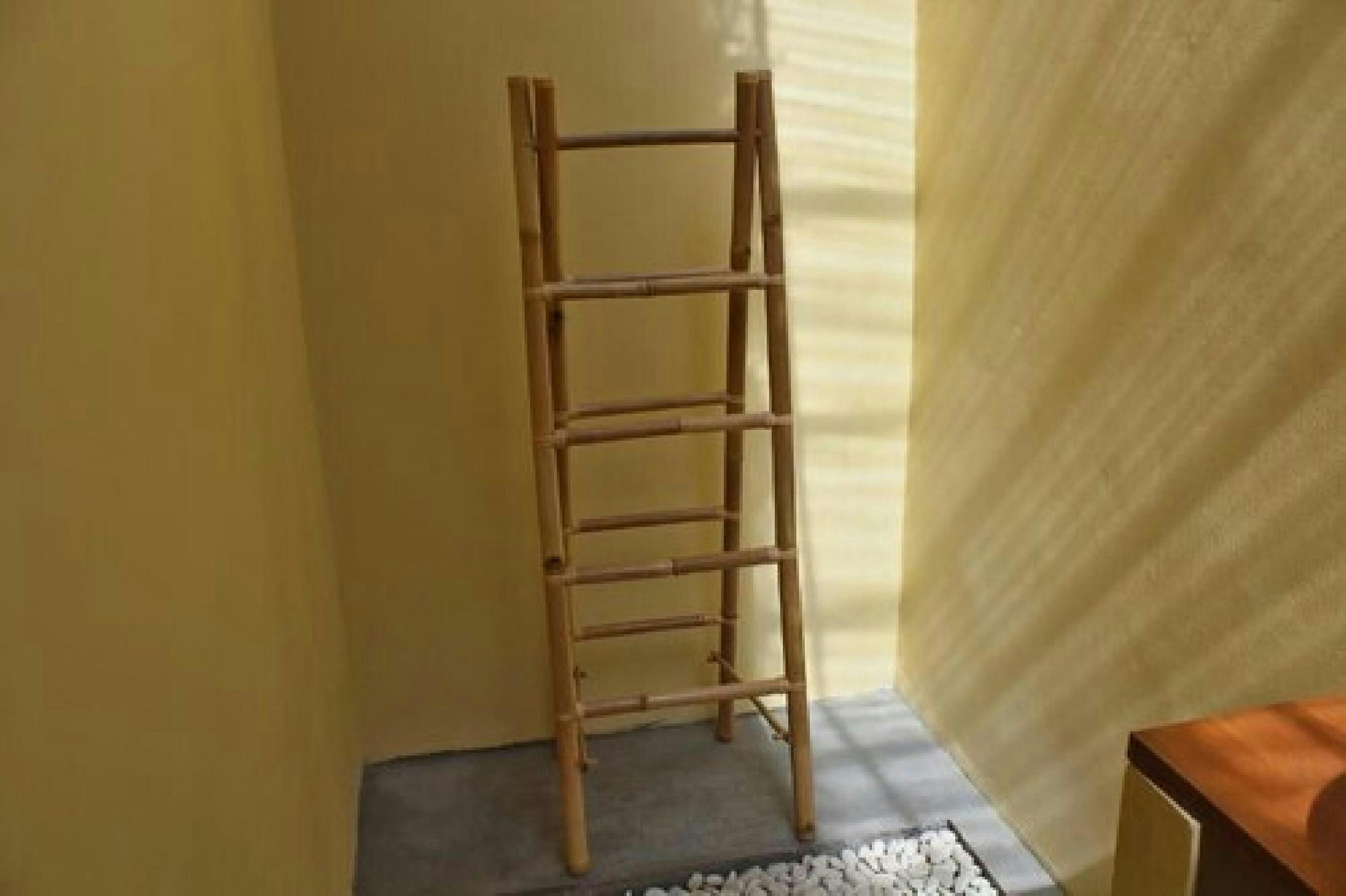 Een houten ladder in een hoek van een kamer met een effen muur en een klein tafeltje.