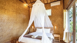 Una habitación con cama bajo dosel, paredes de madera, una mesita de noche pequeña y una ventana con cortinas.