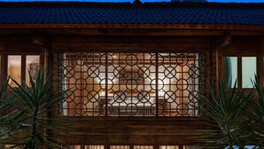 A wooden cabin with a tiled roof, a decorative metal gate, and a mountain in the background. - Yangshuo Secret Garden (Guilin)