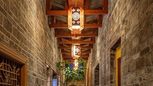 A narrow stone corridor with wooden beams and a lantern hanging from the ceiling. - Yangshuo Secret Garden (Guilin)