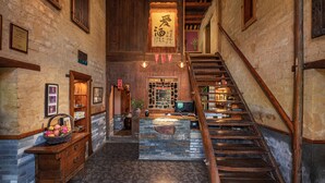 A traditional interior with a wooden staircase, stone counter, and a hanging sign with Chinese characters. - Yangshuo Secret Garden (Guilin)