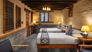 A traditional room with two beds, wooden beams, and a stone wall. - Yangshuo Secret Garden (Guilin)