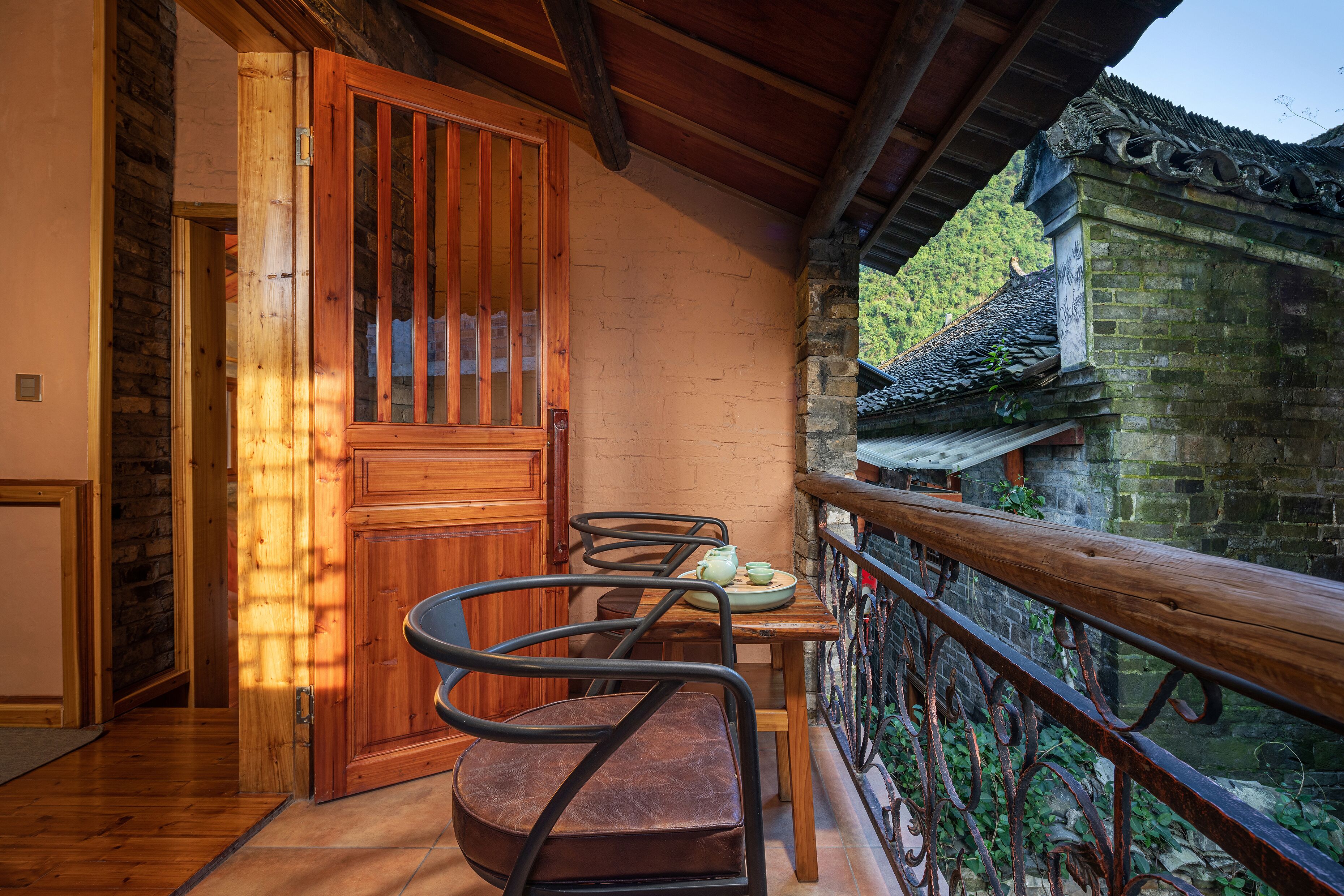Un balcon en bois avec une table et des chaises, une porte en bois et une vue sur un bâtiment traditionnel.