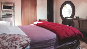 Une chambre à coucher avec un lit, un bureau, une chaise, une fenêtre ronde et une porte.