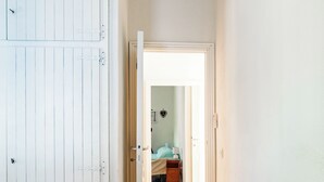 Een slaapkamer met een bed, nachtkastje en een deur naar een andere kamer.