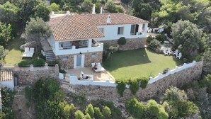 Une maison à deux étages, avec un toit en tuiles, une façade en pierre et une pelouse bien entretenue.