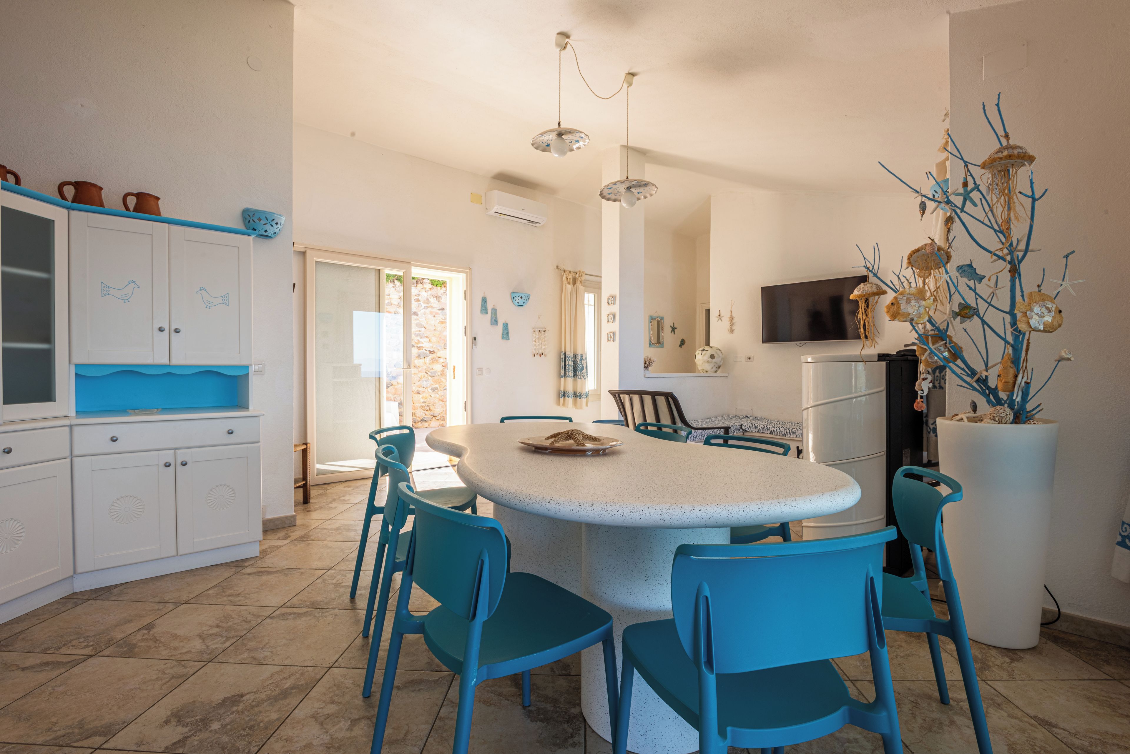 A spacious kitchen with a central island, blue chairs, and a large white refrigerator.