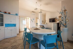 A spacious kitchen with a central island, blue chairs, and a large white refrigerator.