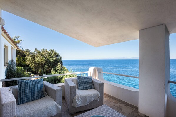 A balcony with wicker furniture and a view of the sea.