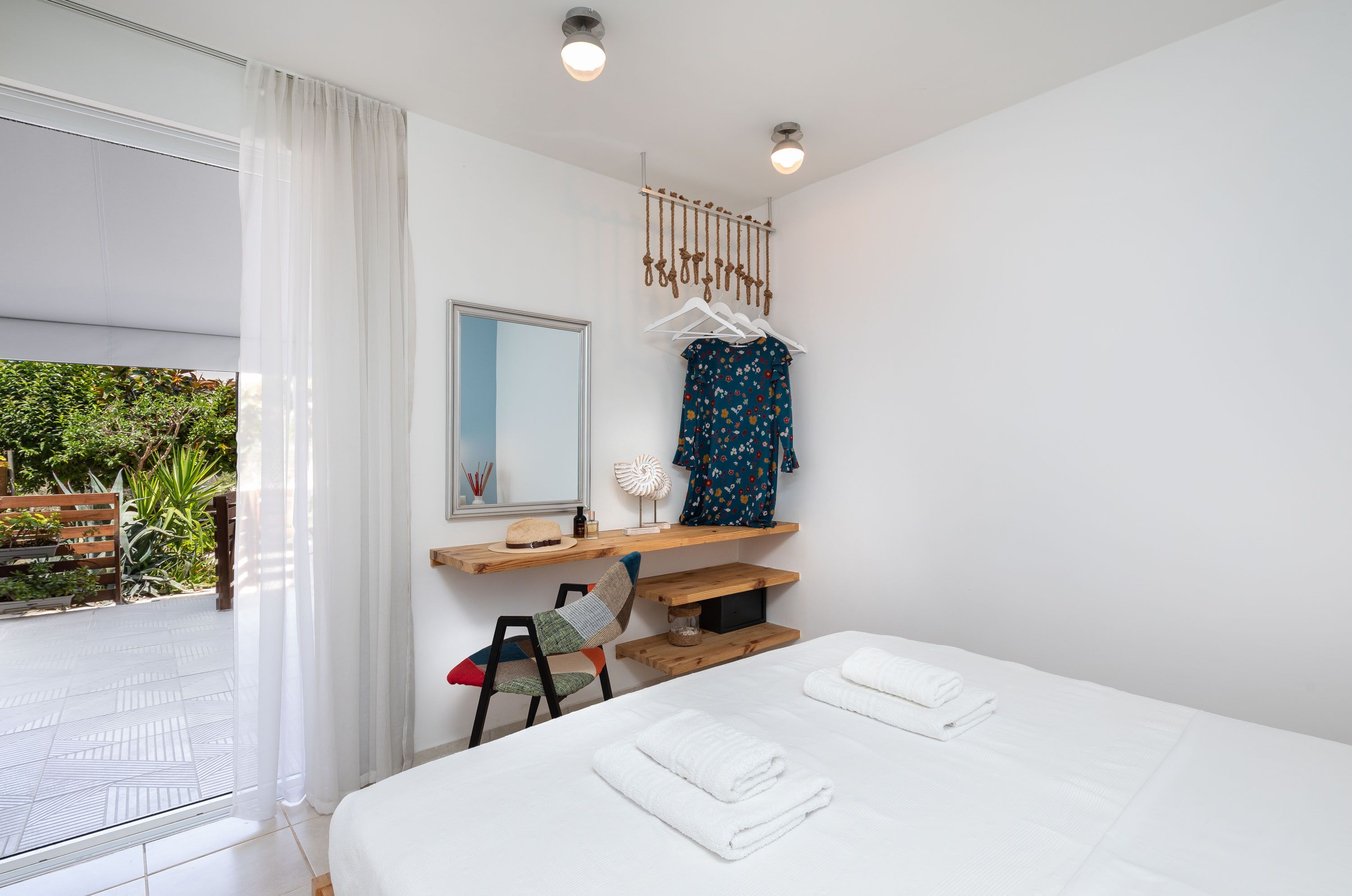 Camera da letto moderna con un letto grande, un comodino in legno, uno specchio e un appendiabiti.