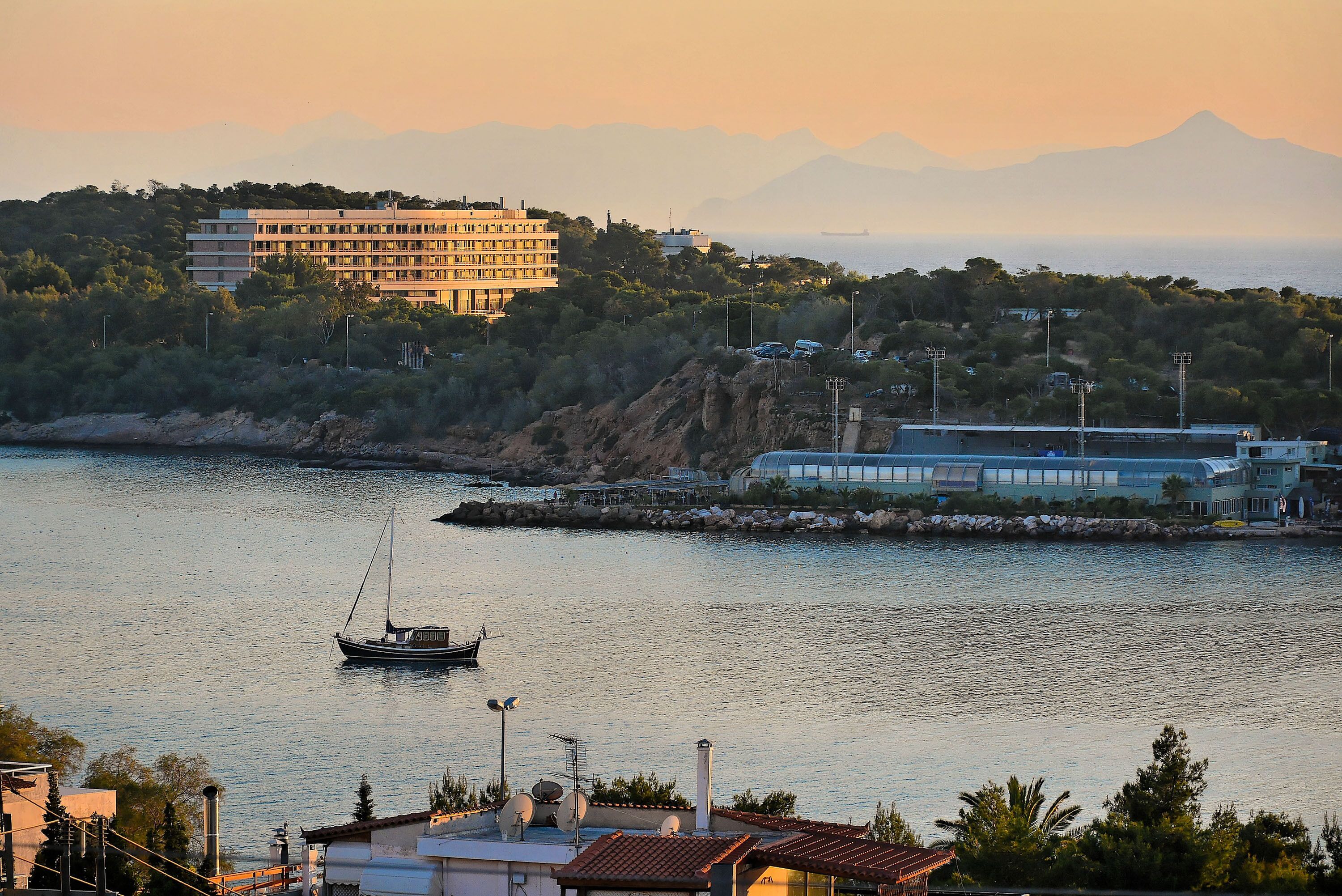 A coastal view with a building, a boat, and a mountain in the background.