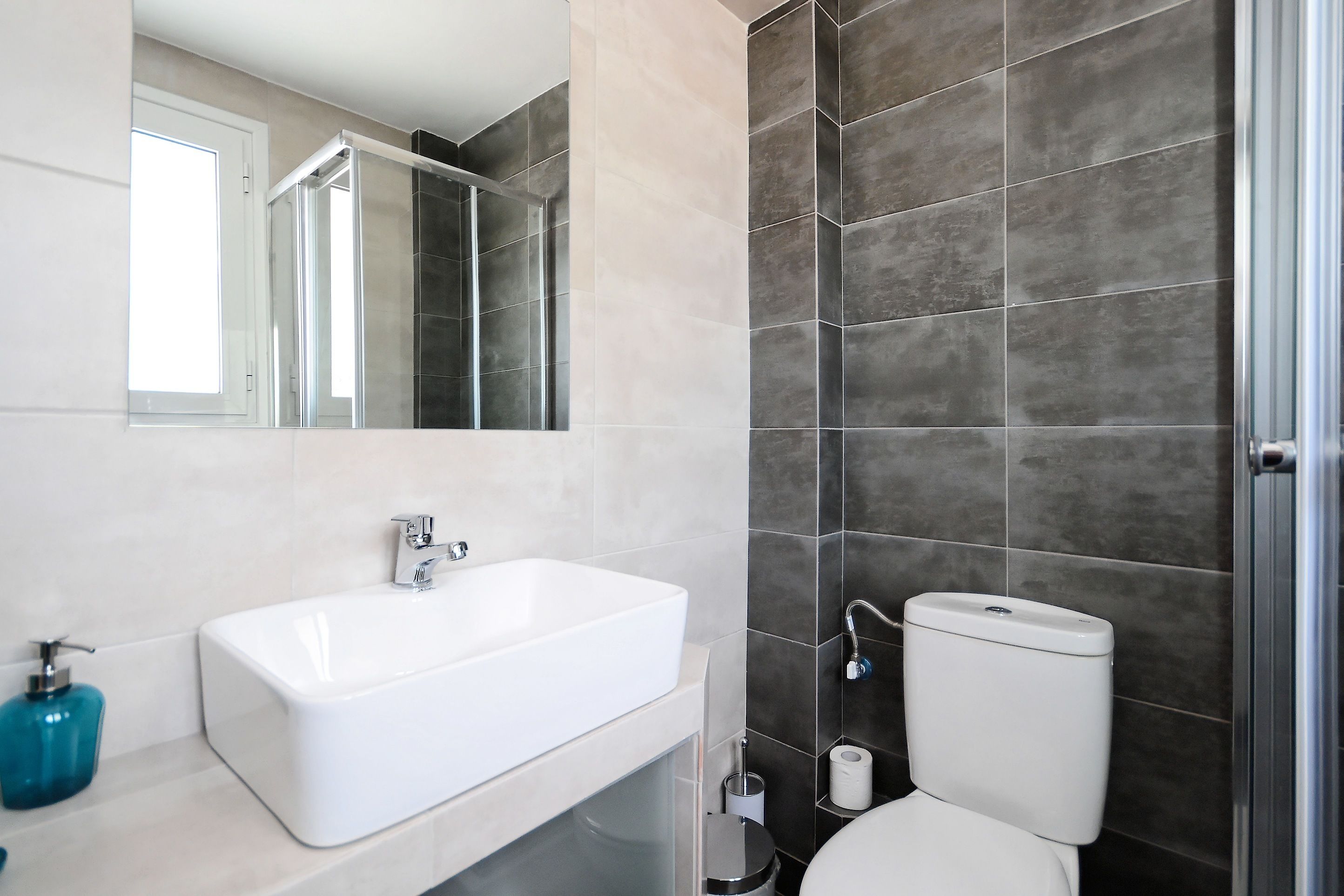 A modern bathroom with a white sink, a toilet, and a mirror.