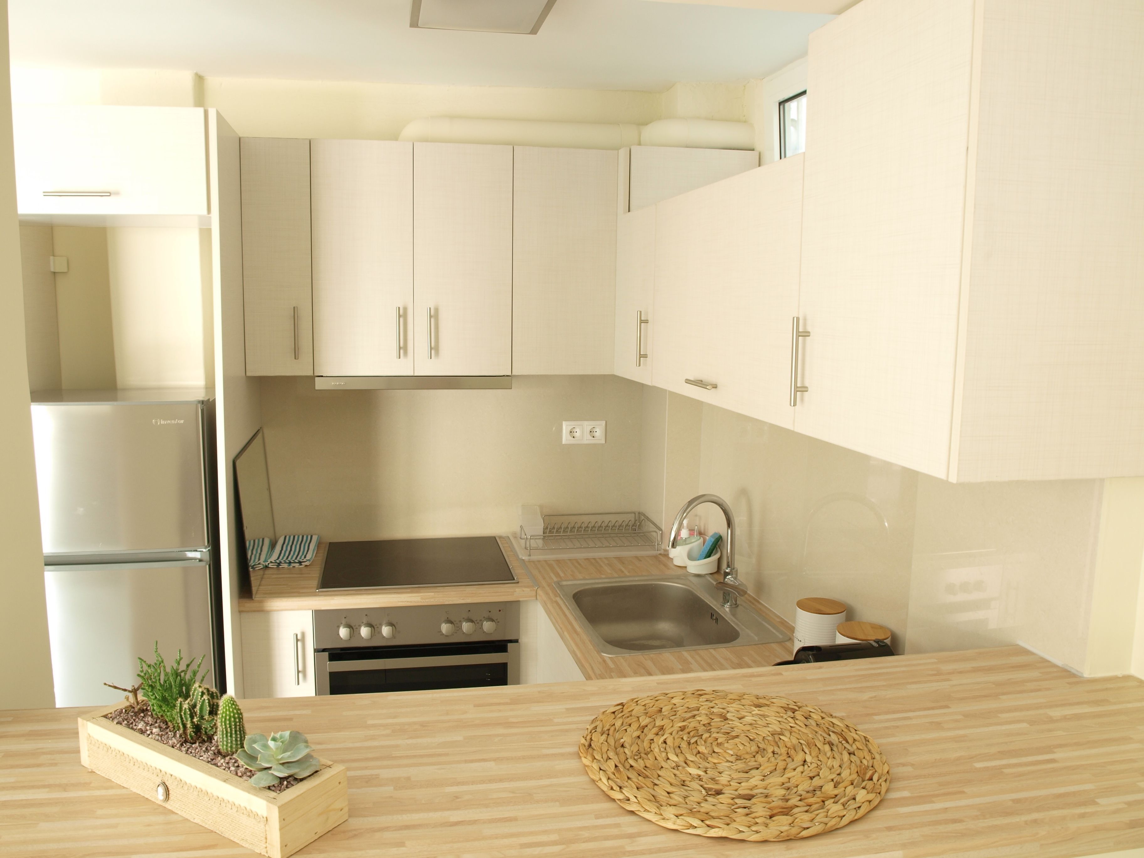 A modern kitchen with light-colored cabinets, stainless steel appliances, and a wooden countertop.