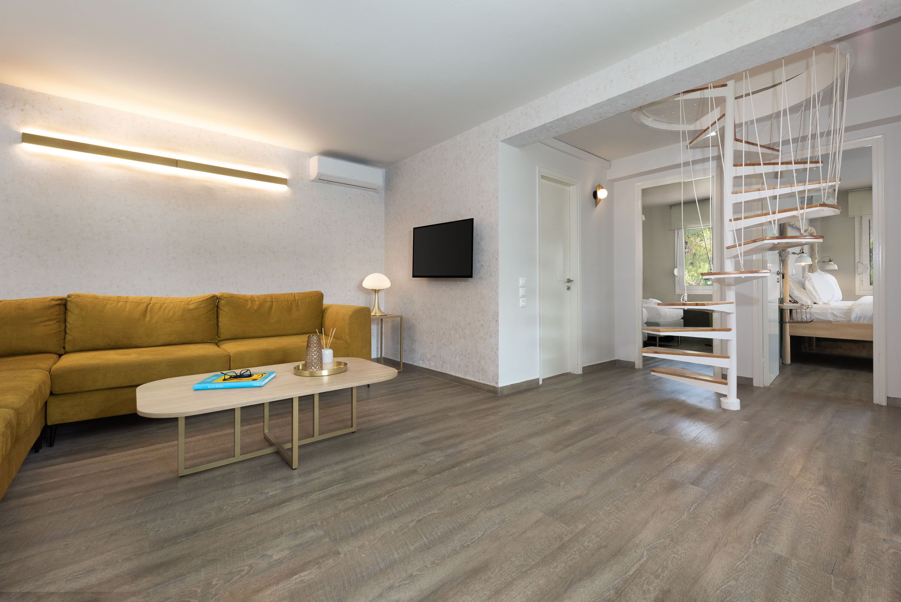 Un salon moderne avec un canapé, une table basse et un escalier en colimaçon original.