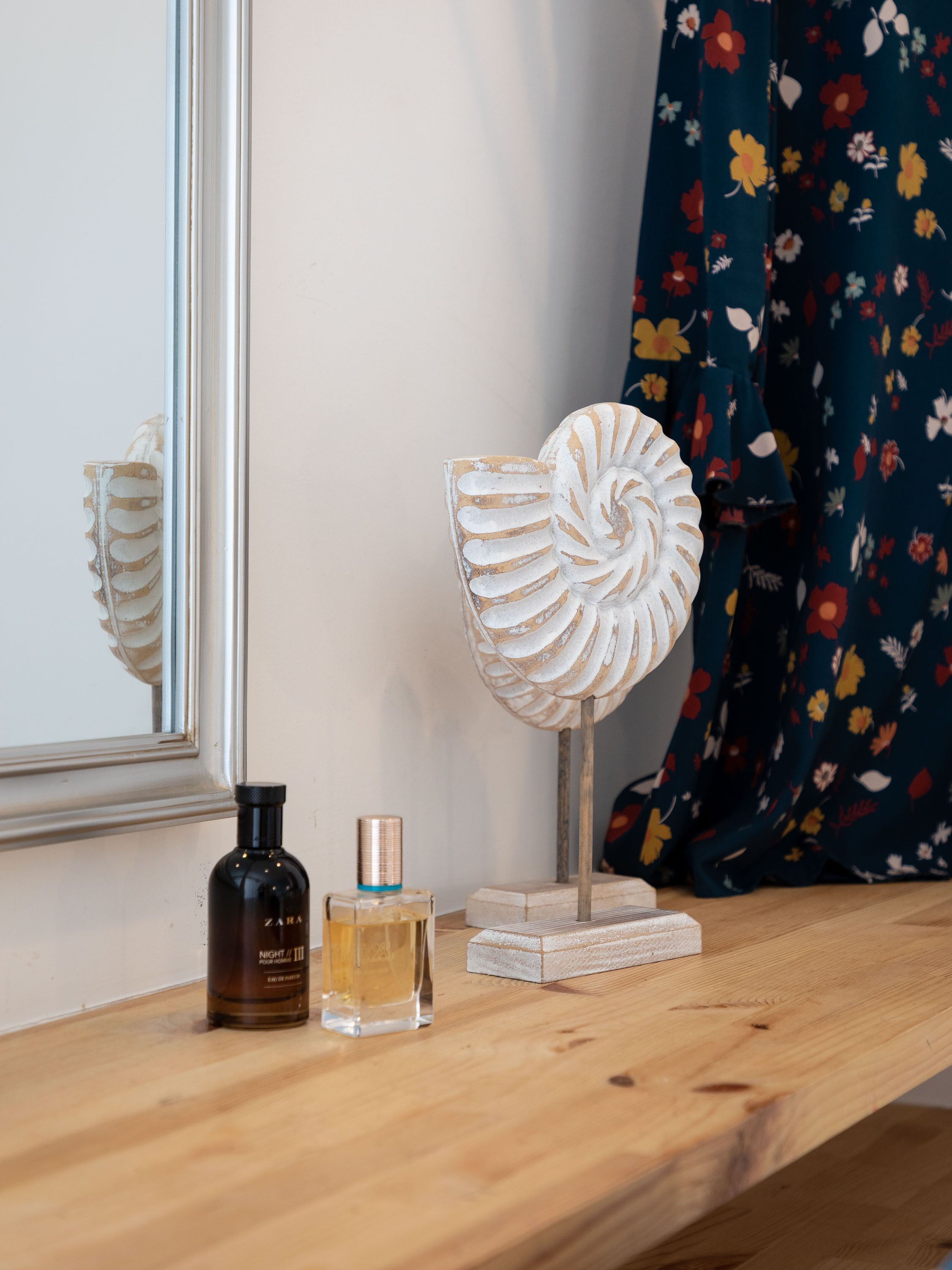 Une étagère en bois sur laquelle se trouvent un flacon de parfum, un flacon en verre et un objet décoratif.