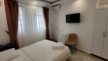 A hotel room with a bed, a chair, a TV, and a wardrobe.