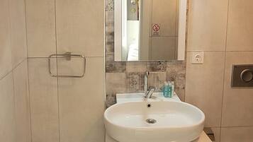 A bathroom with a white sink, mirror, and cabinet.