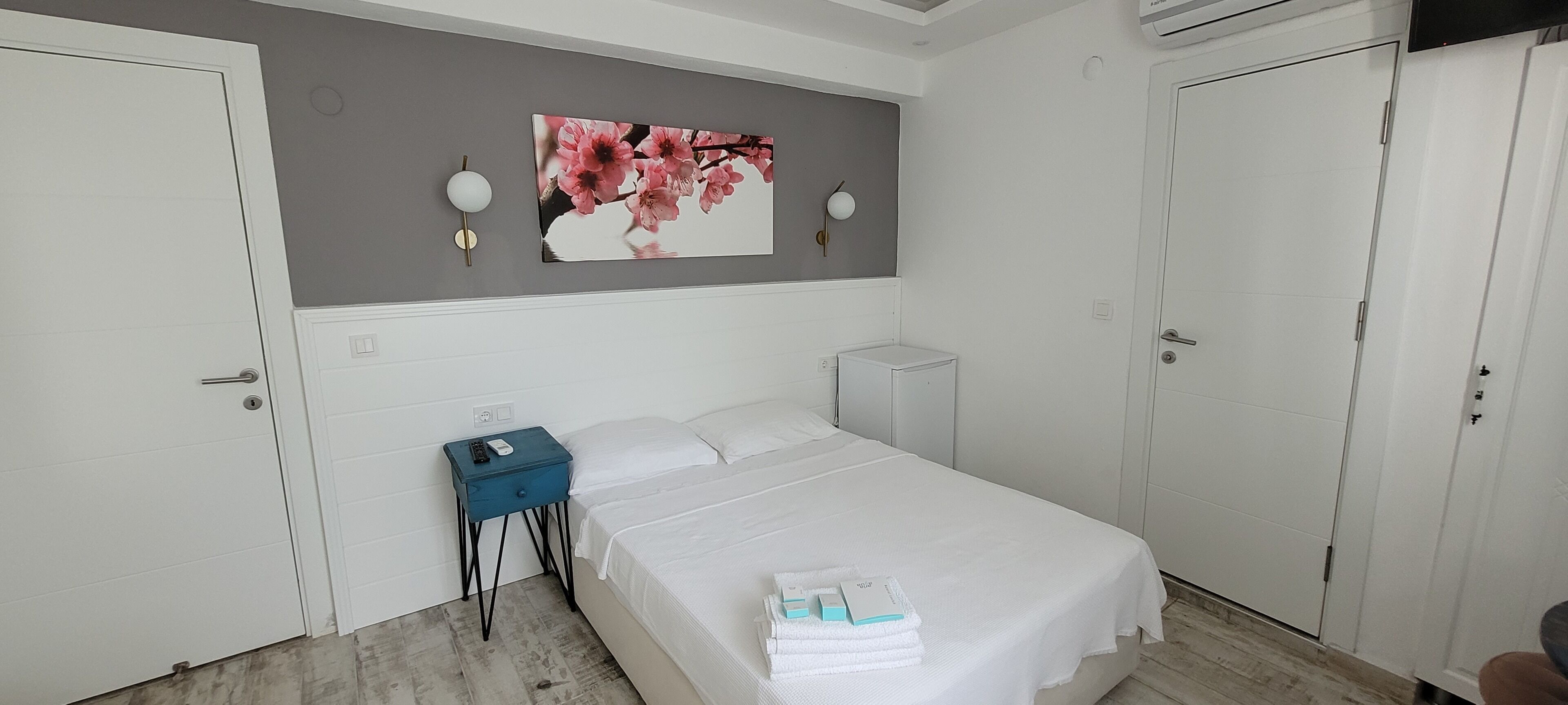 Un dormitorio con una cama, una mesita de noche, una lámpara de pared y un cuadro.