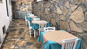 Un patio al aire libre con suelo de piedra y sillas blancas, cada una con un mantel a rayas.