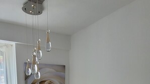 Una escalera con barandilla blanca, una lámpara en el techo y un cuadro grande con motivos florales en la pared.