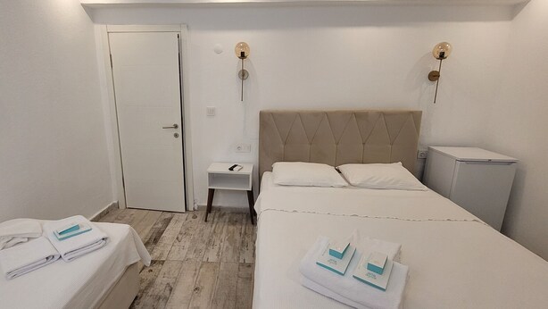 Una habitación de hotel con cama, mesita de noche, armario y un pequeño escritorio.