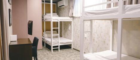 Una habitación con literas, un escritorio y una silla.