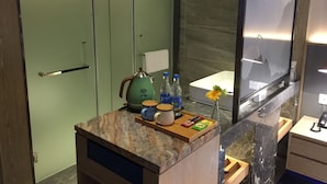 A bathroom with a marble countertop, a green cabinet, a sink, a mirror, and a shower area. - Lifu Hotel Shachong Metro Branch (Guangzhou)