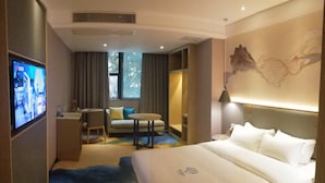 A hotel room with a bed, a desk, a chair, a sofa, and a TV. - Lifu Hotel Shachong Metro Branch (Guangzhou)