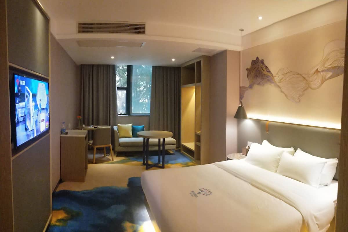 Une chambre d’hôtel équipée d’un lit, d’un bureau, d’une chaise, d’un canapé et d’une télévision.