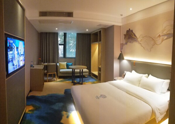 Una habitación de hotel con cama, escritorio, silla, sofá y televisión.