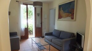 Una sala de estar con un sofá, una mesita, un televisor y un cuadro en la pared.