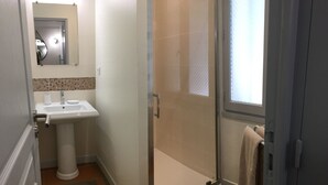 Un baño con lavamanos, espejo y ducha.