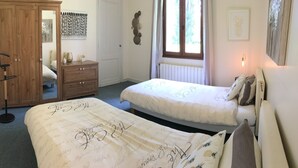 Habitación con dos camas, un armario, un radiador y una ventana con cortinas.