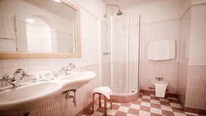 A bathroom with two sinks, a shower, a small toilet, and a mirror. - Hotel Vermoi (Laces)