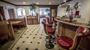 A bar area with leather bar stools, a wooden counter, and a tiled floor. - Hotel Vermoi (Laces)