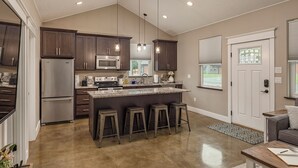 Una cocina moderna con armarios de madera oscura, electrodomésticos de acero inoxidable y una isla central con taburetes de bar.