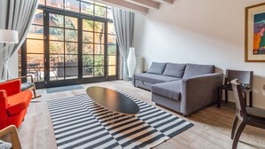 A modern living room with a grey sofa, a red armchair, a black coffee table, and a striped rug. - Bellini 10 - Casin dei Spiriti (Venezia)