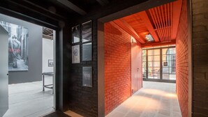 A hallway with a brick wall, a glass door, and a wooden ceiling. - Bellini 10 - Casin dei Spiriti (Venezia)