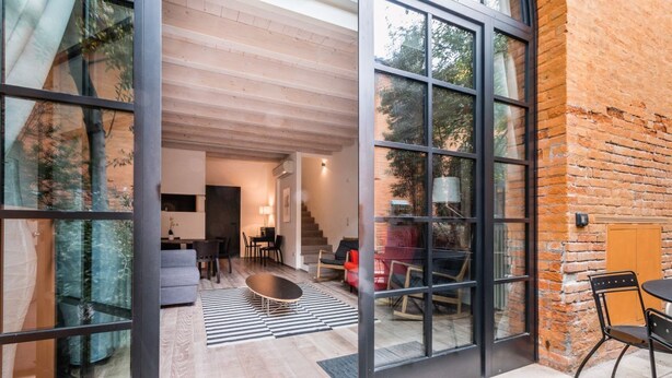 A modern interior with a glass wall, wooden flooring, and a dining area with a table and chairs. - Bellini 10 - Casin dei Spiriti (Venezia)