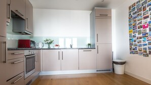 A modern kitchen with stainless steel appliances, light-colored cabinets, and a wooden floor. - Modern apartment with great views (London)