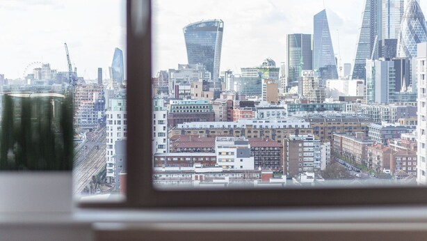 A cityscape through a window with modern buildings, including a distinctive curved skyscraper. - Modern apartment with great views (London)